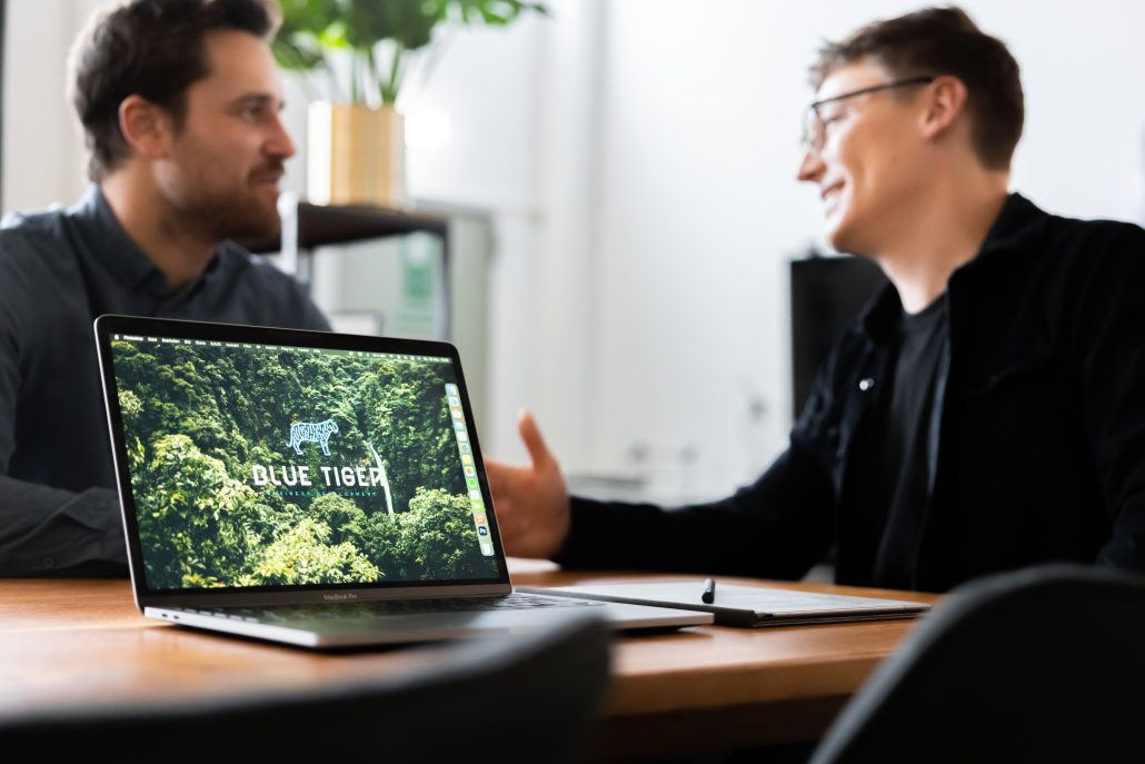 Two people talking happily while a laptop sits in front of the image